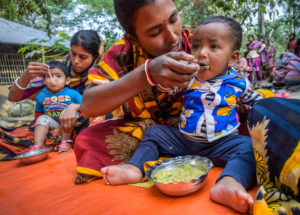 Mother feeds her baby nutritious food in Bangladesh.