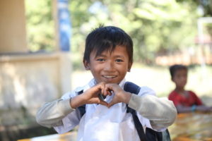 young boy in Cambodia makes "heart hands"